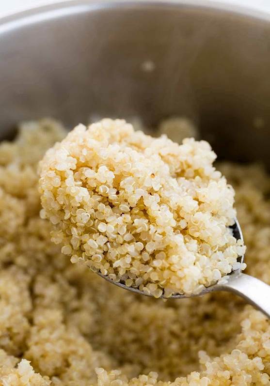 Metal spoon holding up a scoop of cooked quinoa.