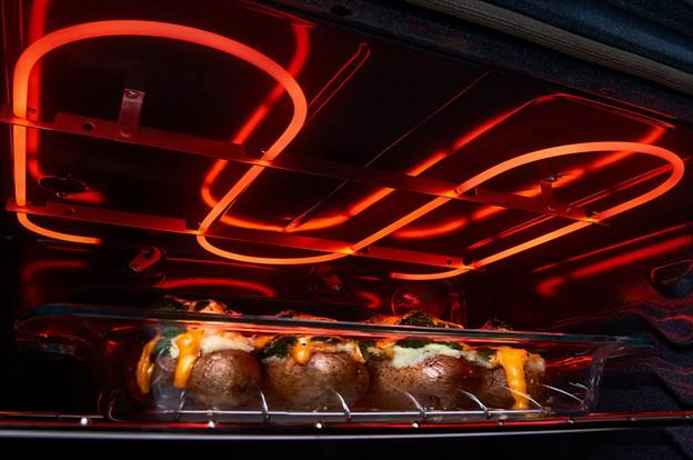 A broiler element broiling baked potatoes in an oven