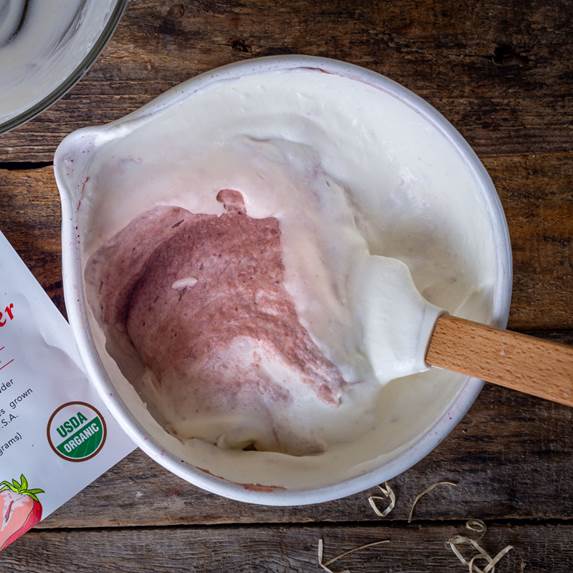 Ancient Choice organic strawberry powder with strawberry ice cream mix on wooden table.